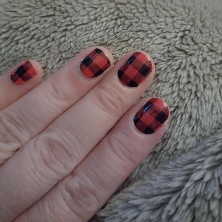 Close-up of red and black tartan check nail wraps on fingertips