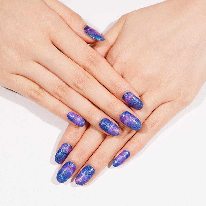 Blue purple magnetic nail wraps with chrome shimmer finish on hands showing at-home manicure