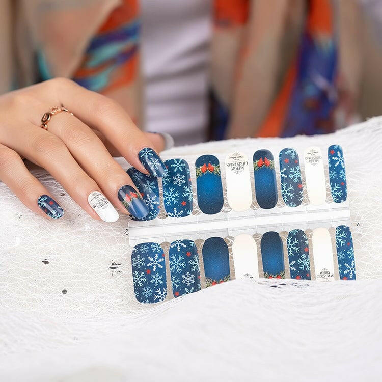 Sheet of blue Christmas nail wraps with snowflake patterns and holiday designs for at-home manicure