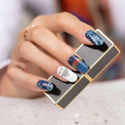 Hand holding compact mirror wearing blue Christmas nail art with snowflake and bow patterns
