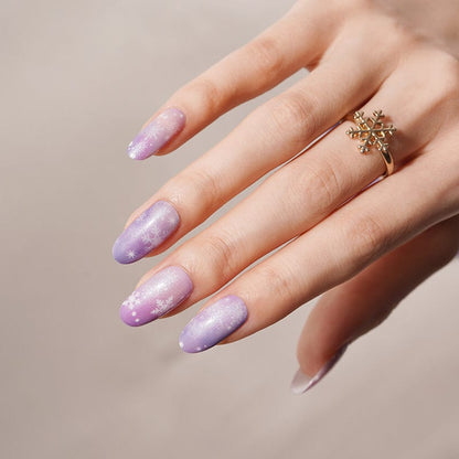 Purple sparkle nail wraps with snowflake nail art on hand wearing gold snowflake ring