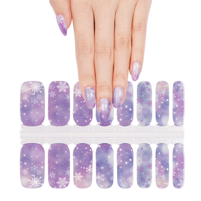 Hand demonstrating purple gradient nail wraps with white snowflake Christmas nail art design