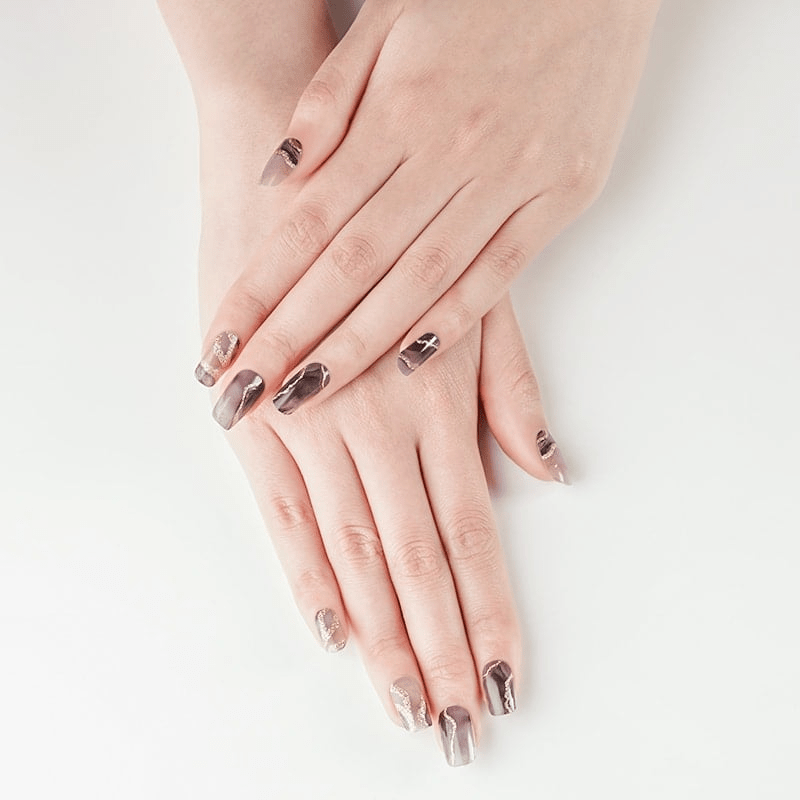 Two hands displaying black marble nail art wraps with rose gold veining manicure