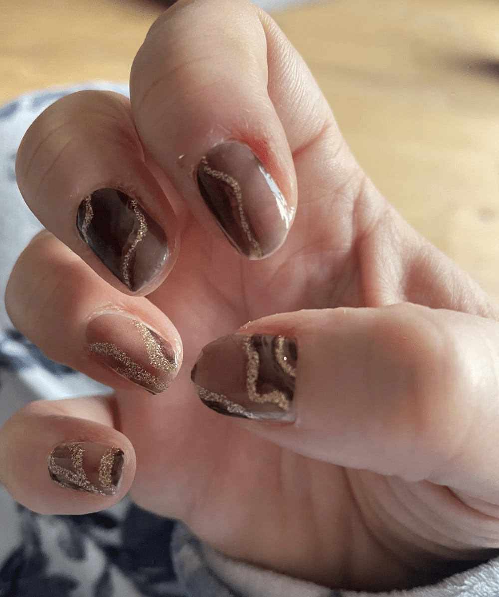 Dark marble nail wraps with rose gold veining on hand showing dramatic manicure