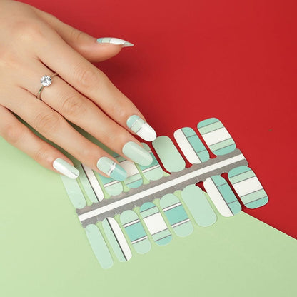 Mint green striped nail wraps on hand with matching sheet on red background