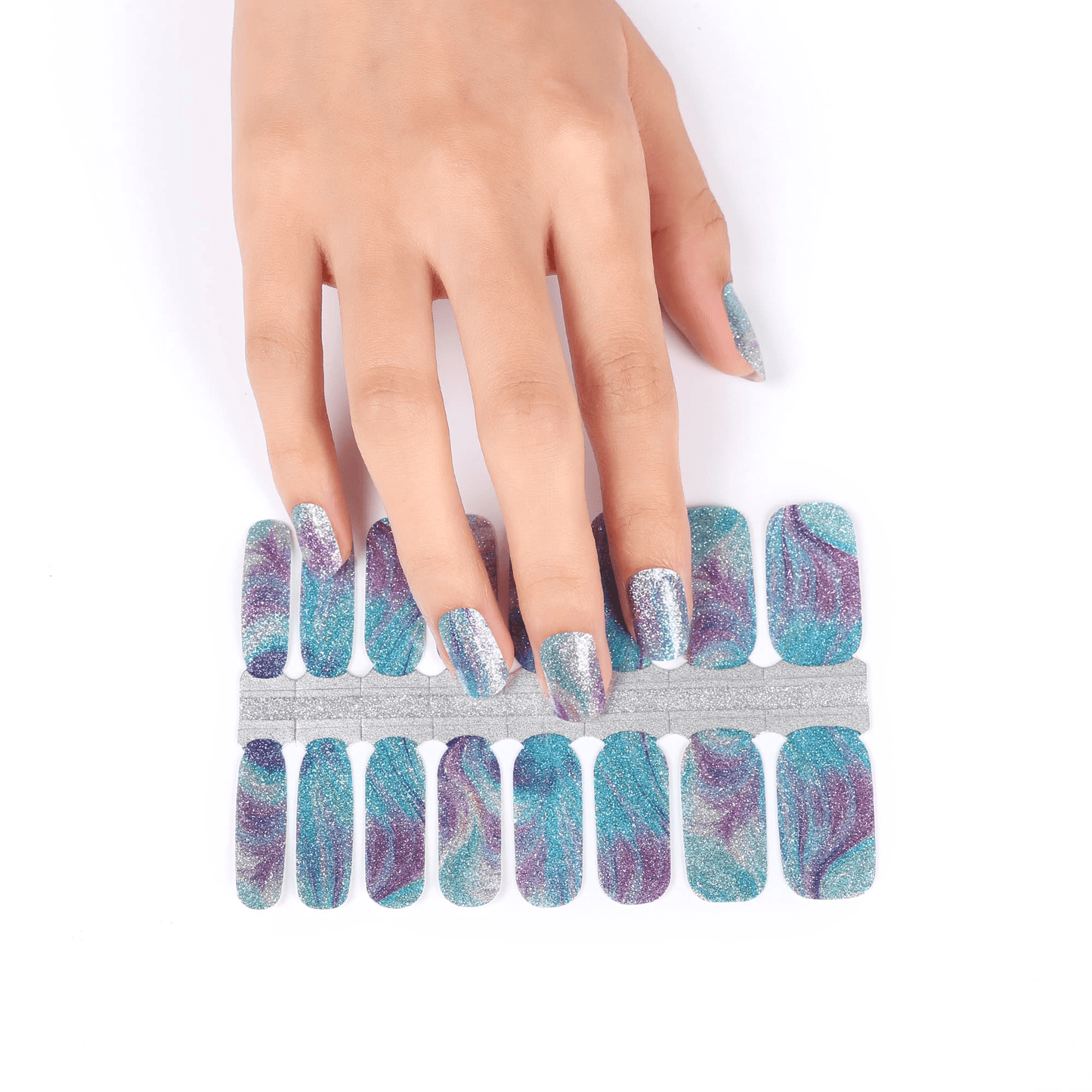 Hand applying teal holographic nail wraps with blue glitter sparkle pattern strips