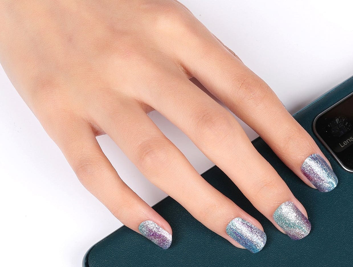 Holographic blue glitter nail wraps on hand creating shimmery mermaid-inspired manicure