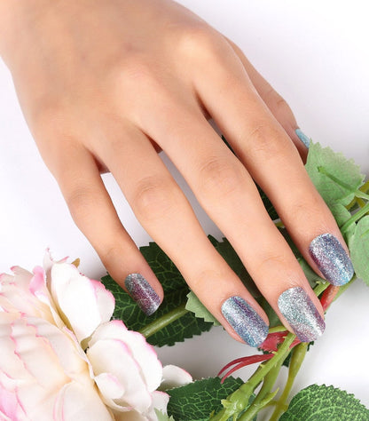Sparkly blue holographic gel nail wraps displayed on hand with white flowers