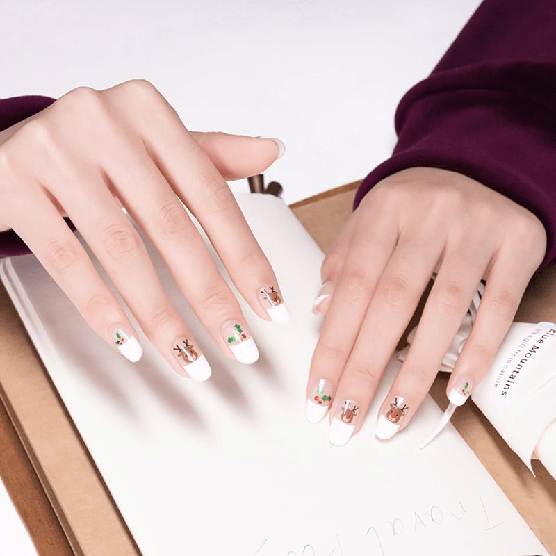 Christmas nail art on hands featuring white French tips with festive mistletoe and reindeer designs