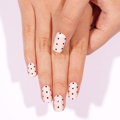 White nail wraps with black polka dots shown on hand, minimalist at-home manicure design