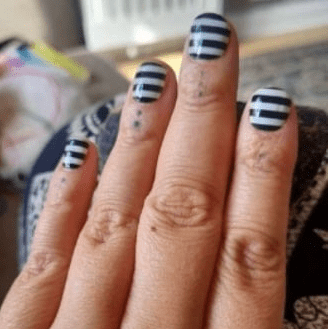 Hand wearing black and white striped non-UV nail wraps geometric pattern