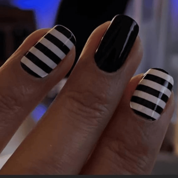 Close up hand showing black and white striped nail art wraps