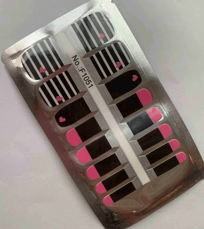 Black and white striped nail wraps with pink hearts in packaging for pedicures