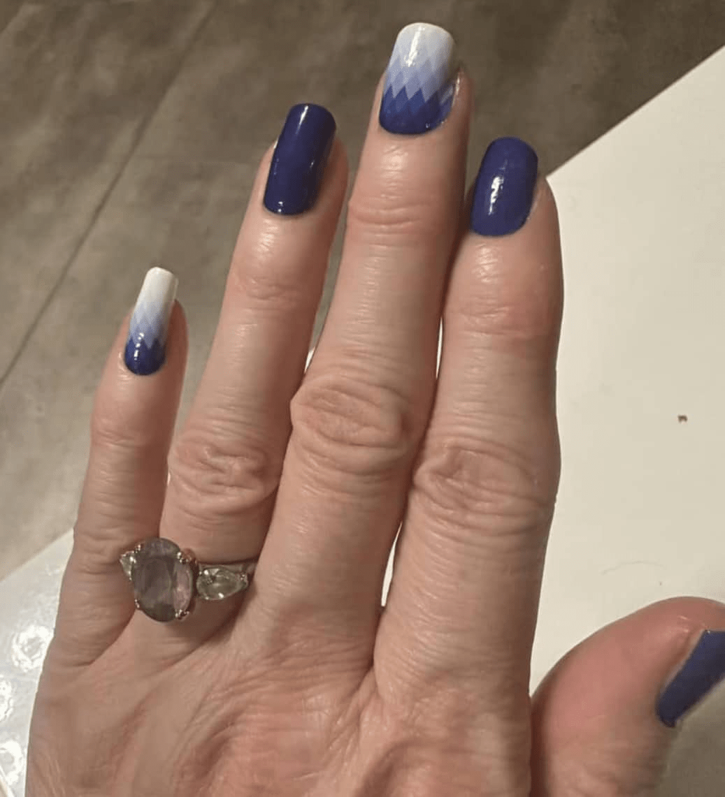 Blue gradient nail art wraps on hand showing ombre manicure design with white tips