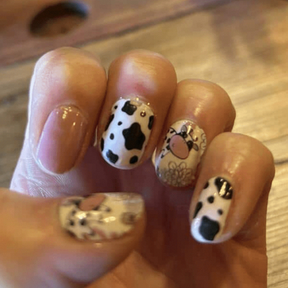 Kawaii cow nail wraps on fingernails featuring adorable cartoon farm animal designs