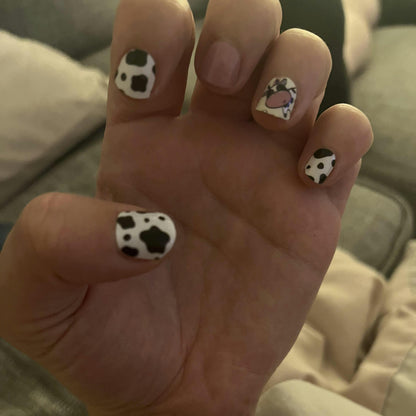 Black and white cow print nail wraps applied on hand showing spotted pattern