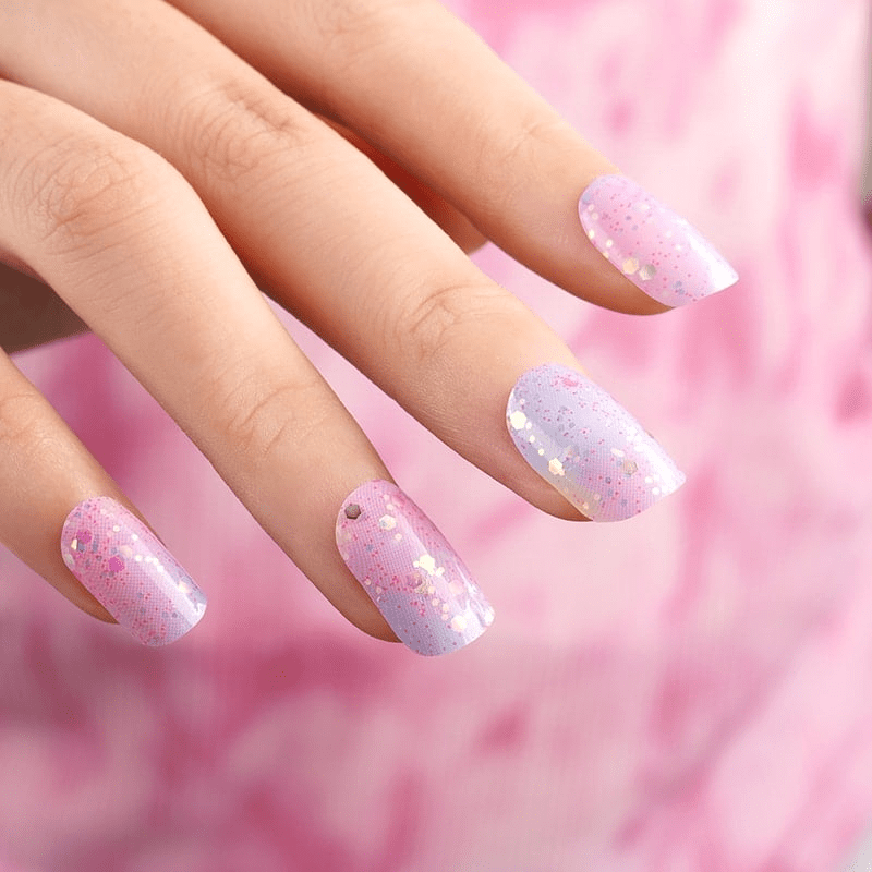 Pink gradient gel nail wraps with metallic dots applied on natural nails manicure