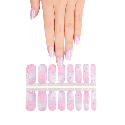 Hand wearing pink blue ombre glitter nail wraps with cosmic nail art pattern sheet
