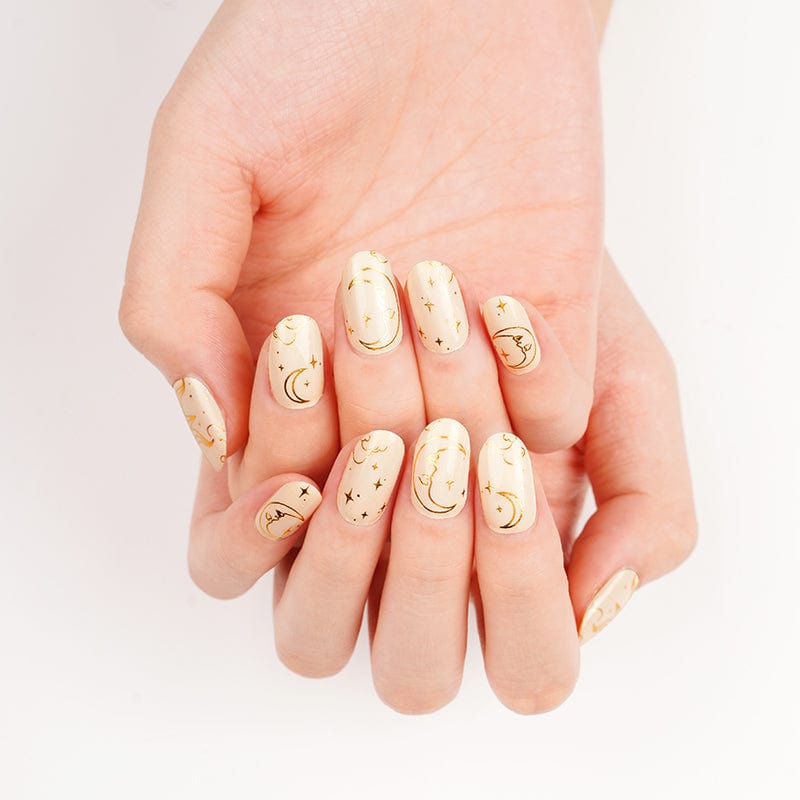 Gold celestial nail art wraps with moons and stars on natural nude manicure