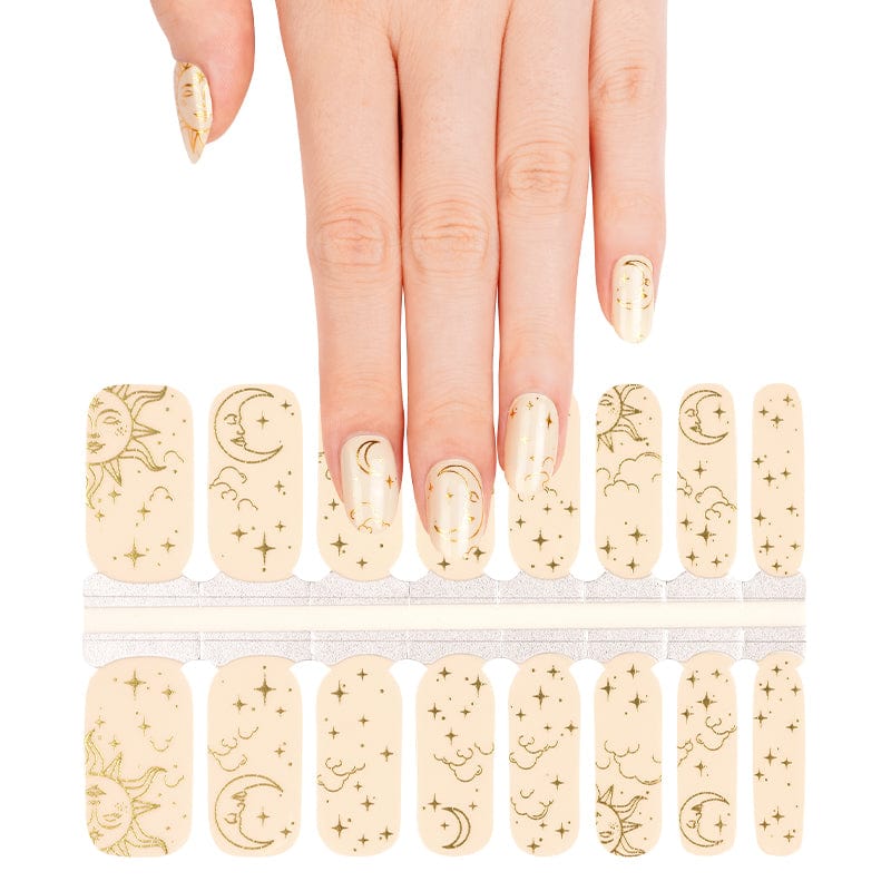 Hand selecting celestial nail wraps from sheet featuring gold astronomical line art designs