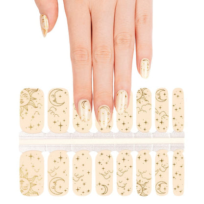 Hand selecting celestial nail wraps from sheet featuring gold astronomical line art designs