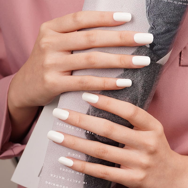 Mother of pearl white nail wraps on hands holding magazine showing classic manicure