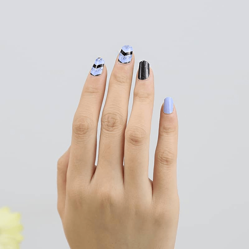 Hand showing blue and black chevron geometric nail wraps with matte finish
