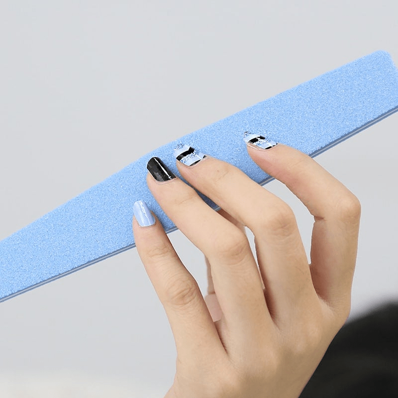 Hand displaying blue black chevron nail art wraps for at-home manicure