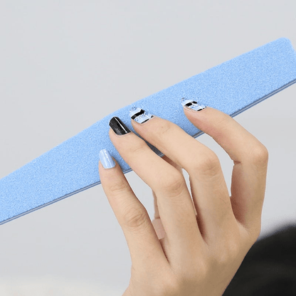 Hand displaying blue black chevron nail art wraps for at-home manicure