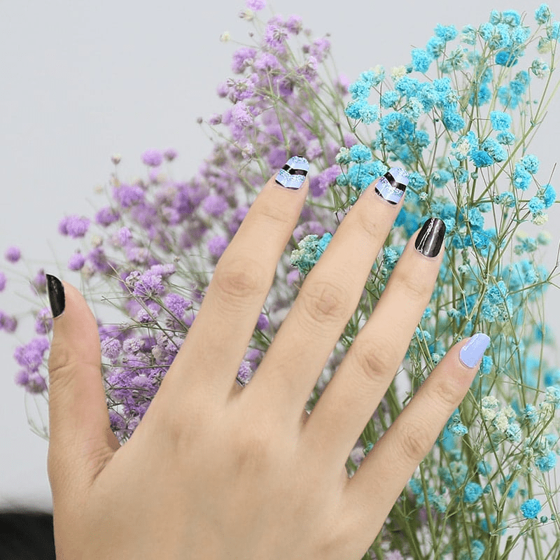 Blue black chevron nail wraps on hand amongst purple and turquoise flowers