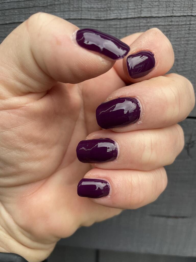 Deep mulberry purple glossy nail wraps on hand showing elegant at-home manicure