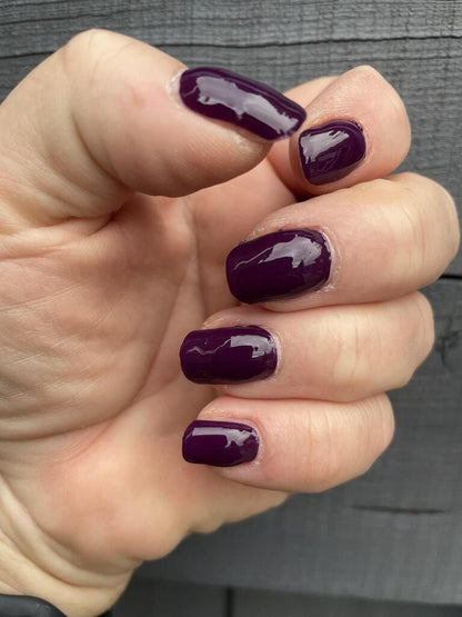 Deep mulberry purple glossy nail wraps on hand showing elegant at-home manicure