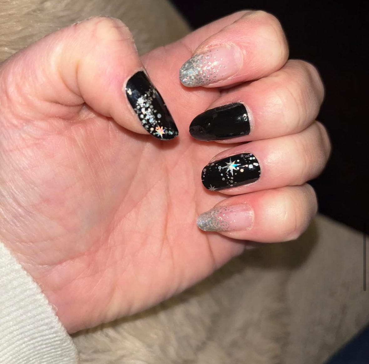 Black and silver glitter star nail wraps on hand showing celestial at-home manicure design