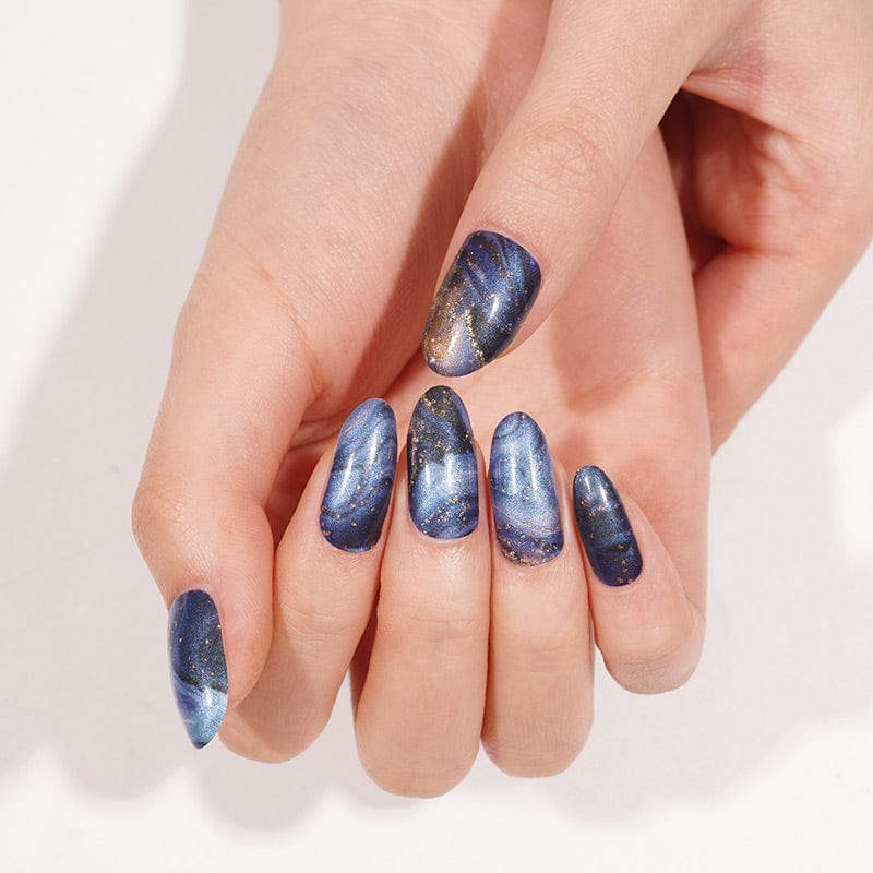Navy blue marble nail wraps on hand with copper metallic veining and elegant finish