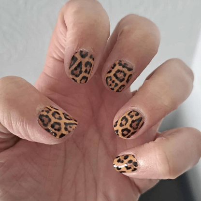 Hand showing leopard print nail wraps in brown and black animal pattern
