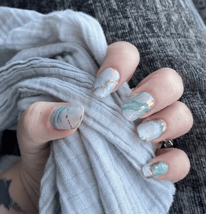 Blue marble nail wraps manicure on hand with abstract watercolour stone effect design