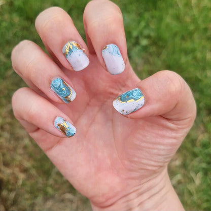 Blue marble nail wraps on hand showing abstract watercolour stone effect manicure design
