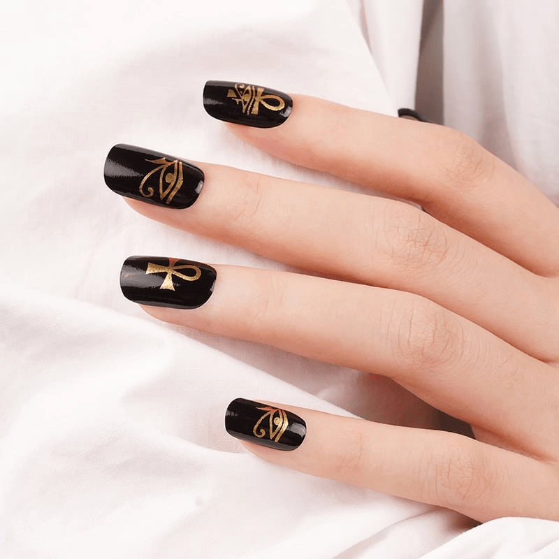 Black matte nail wraps with gold Egyptian symbols on hand showing ankh designs