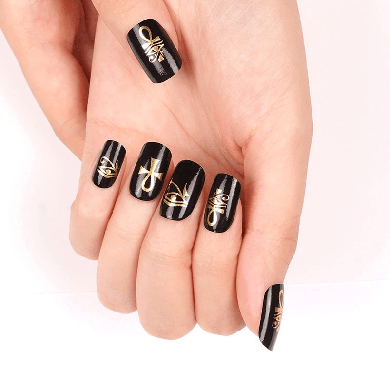 Egyptian themed nail wraps in black with gold hieroglyphic symbols on hands