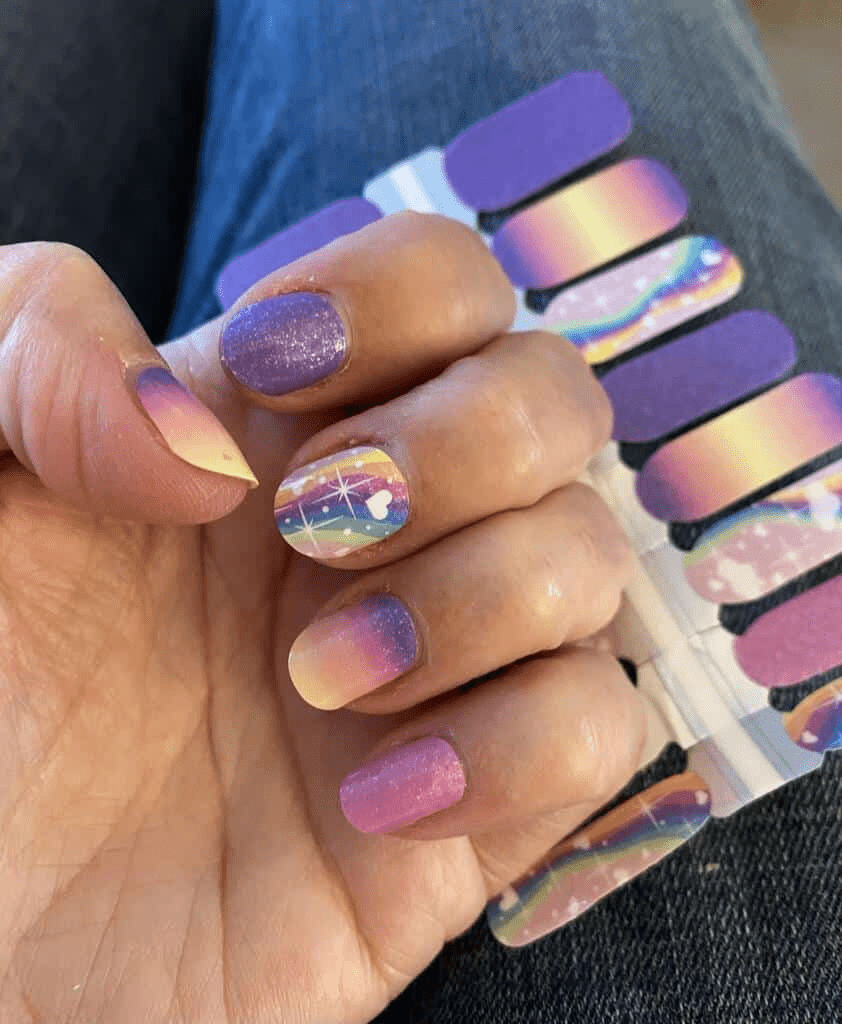 Hand wearing rainbow gradient nail wraps with purple pink yellow holographic nail art