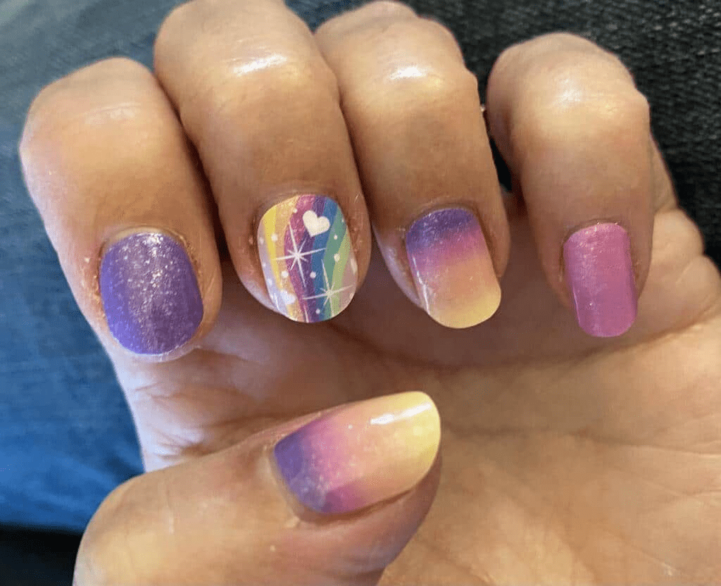 Rainbow gradient nail wraps applied on hand showing purple pink yellow manicure design