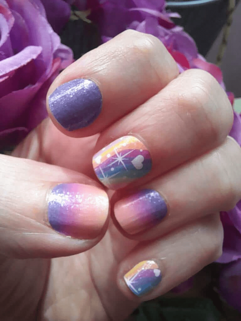 Hand displaying purple pink gradient nail art with holographic rainbow star patterns on fingernails