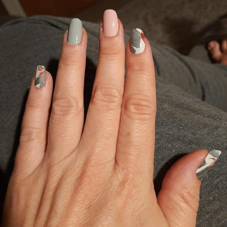 Hand displaying botanical nail wraps with sage green base and white palm leaf pattern designs