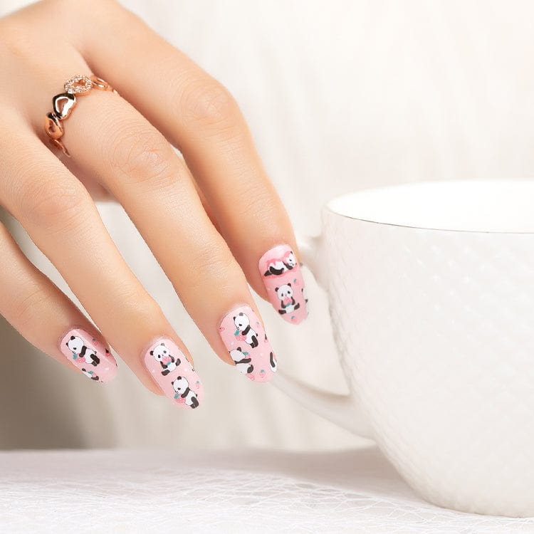 Hand wearing adorable panda nail wraps in pink with cartoon animal design