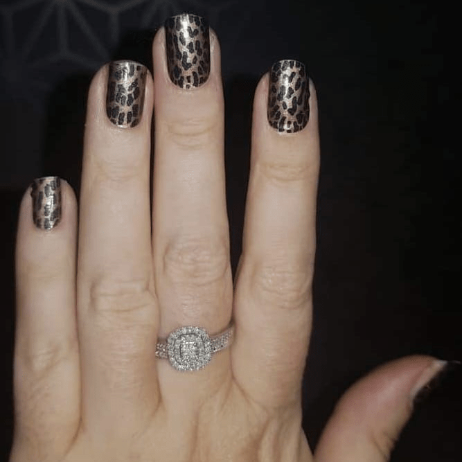 Hand wearing leopard print nail wraps with diamond ring showing animal print nail art