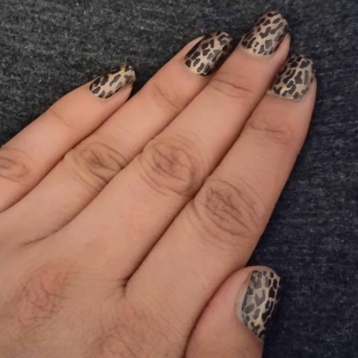 Leopard print nail wraps applied on hand showing brown tan animal print pattern