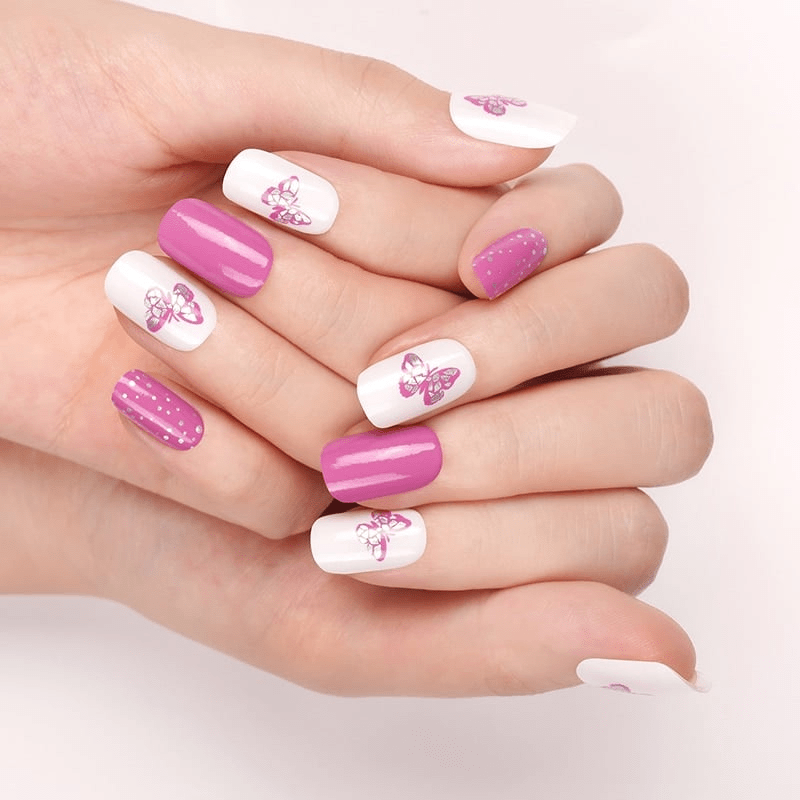 Pink butterfly nail wraps on hand showing mixed polka dot and solid manicure design
