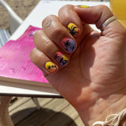 Paradise island nail wraps on hand showing tropical sunset gradient with palm trees