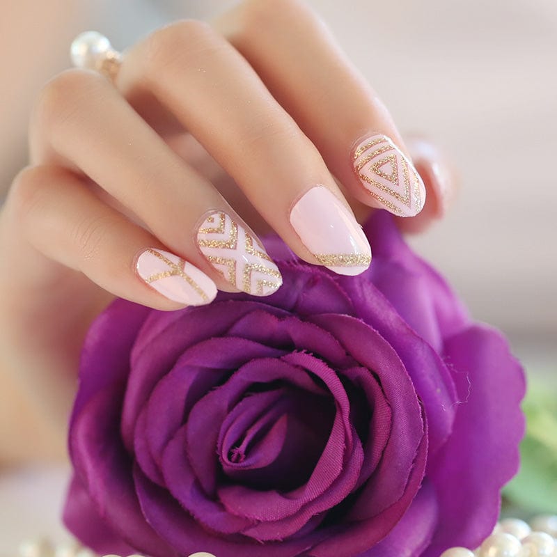Pink and gold patterned gel nail wraps on hand beside purple rose