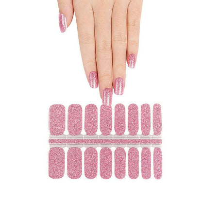 Hand above pink glitter nail wrap sheet showing individual nail strips